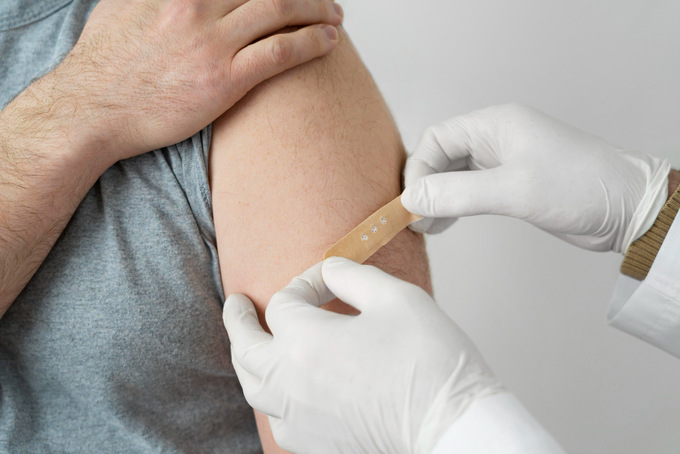 doctor-putting-bandage-male-patient-s-arm-after-vaccine-shot