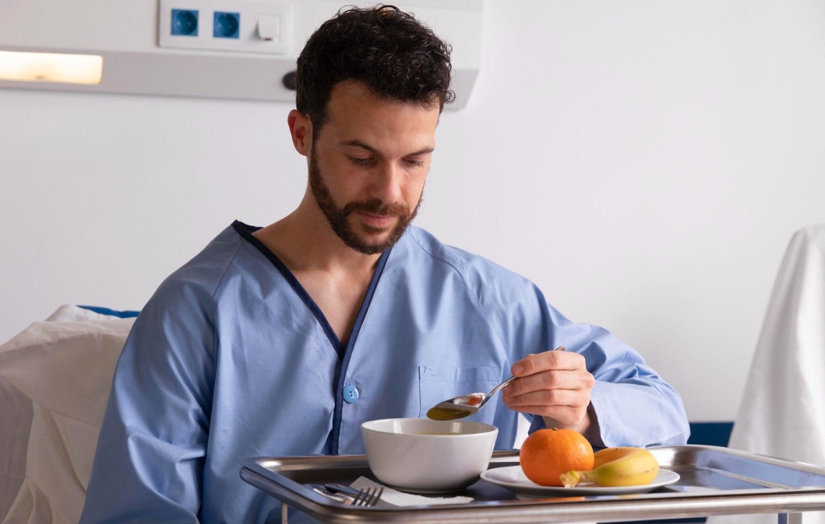 a person in a light blue hospital gown eating a meal