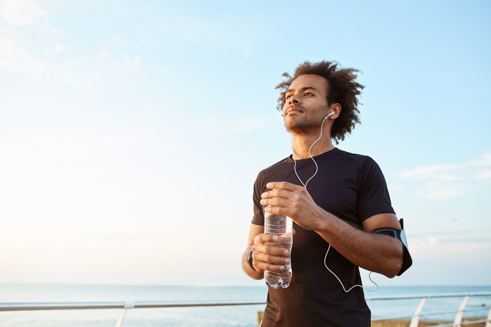 man-athlete-drinking-water-out-plastic-bottle-after-hard-running-workout-dark-skinned-male-sportsman-looking-sky-while-running-enjoying-view-1.jpg