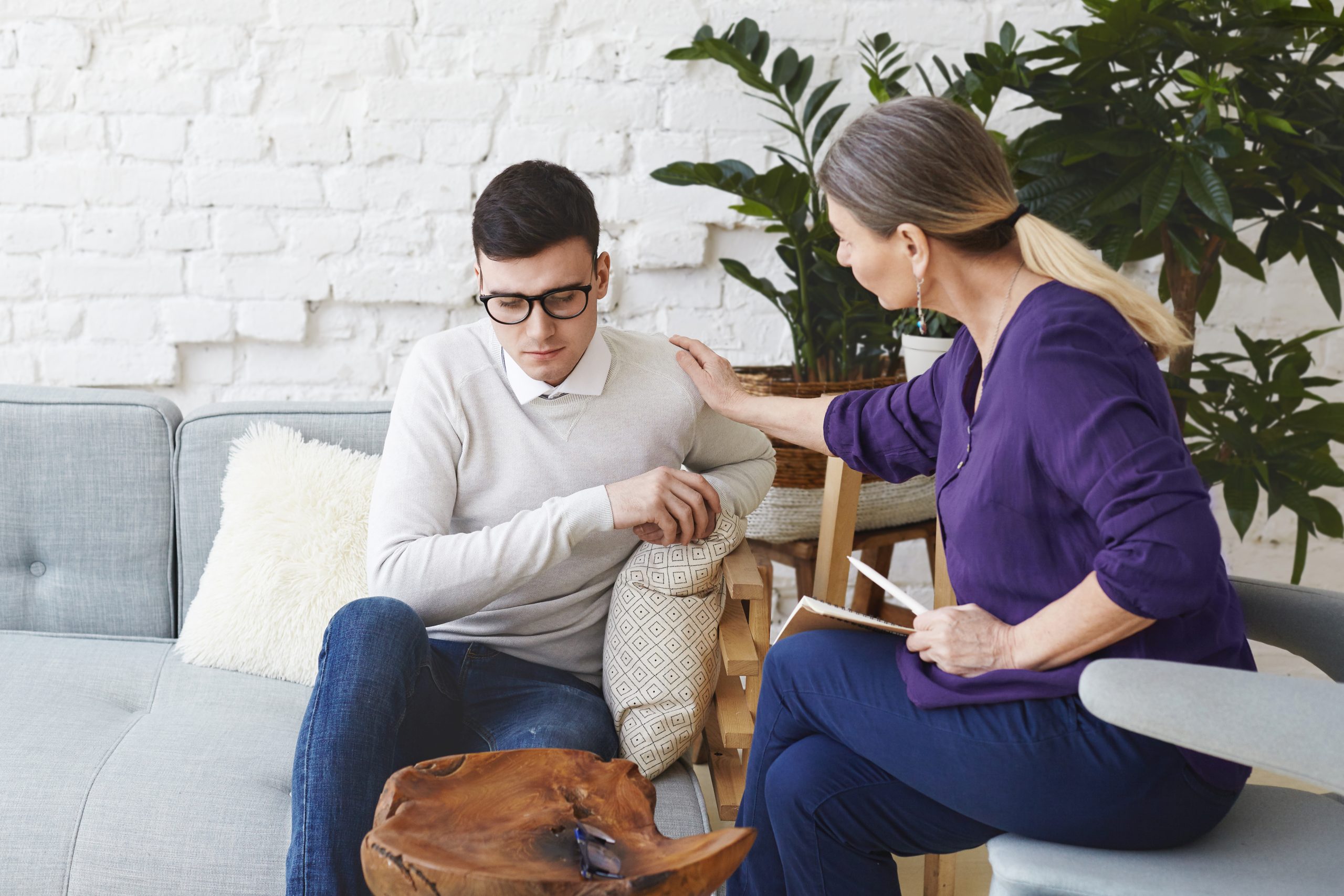 candid-shot-casually-dressed-professional-woman-psychotherapist-her-fifties-touching-her-young-male-patient-by-shoulder-while-having-counseling-session-expressing-sympathy-support-scaled.jpg