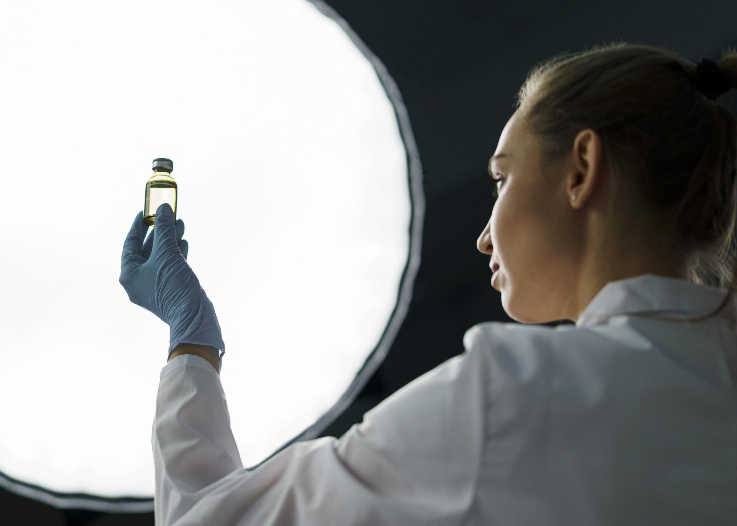 female-researcher-laboratory-holding-vaccine-bottle-light-scaled.jpg