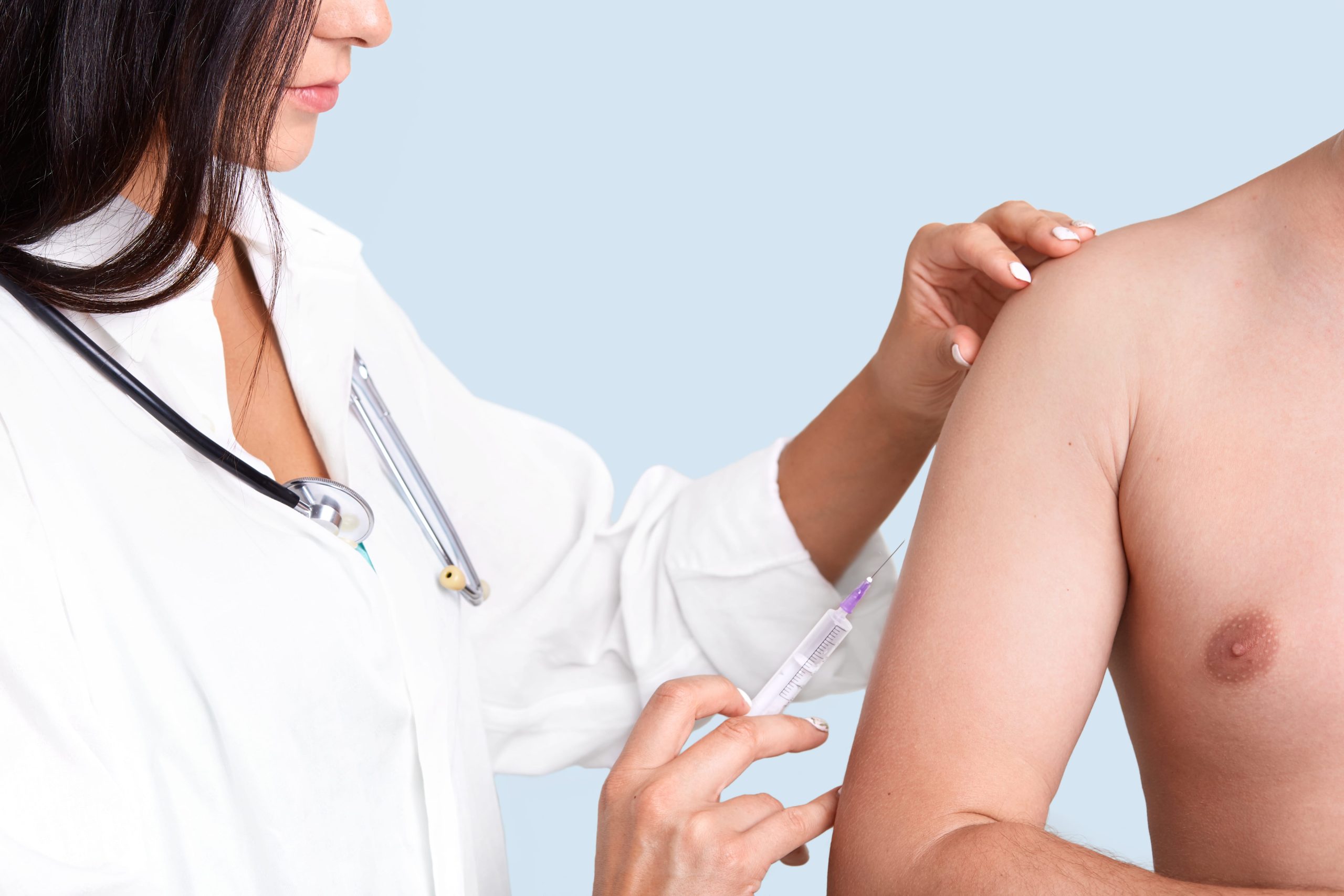photo-brunette-female-nurse-white-gown-with-phonendoscope-makes-vaccination-arm-patient-min-scaled.jpg