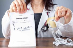 Doctor holding lose weight prescription and measuring tape