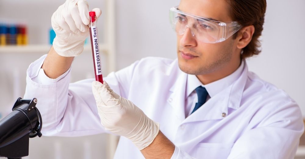A man in a lab coat and safety glasses holds up a test tube labeled "TESTOSTERONE Test" 