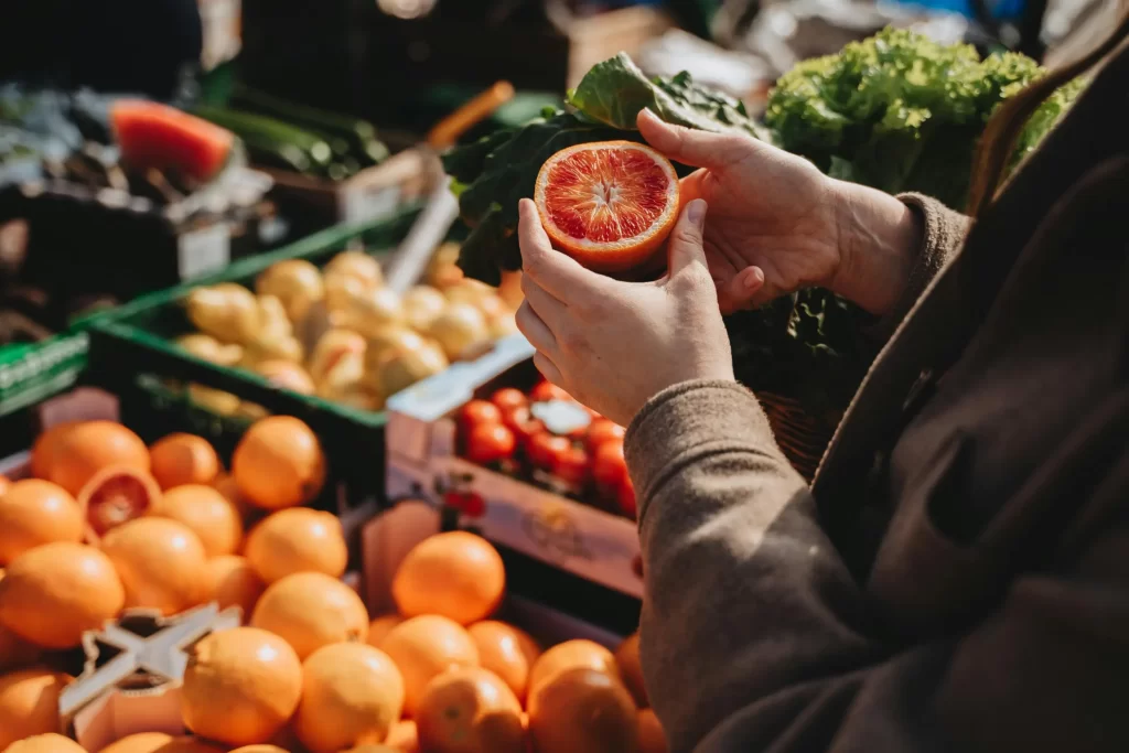 A person in a brown coat holding up a halved blood orange