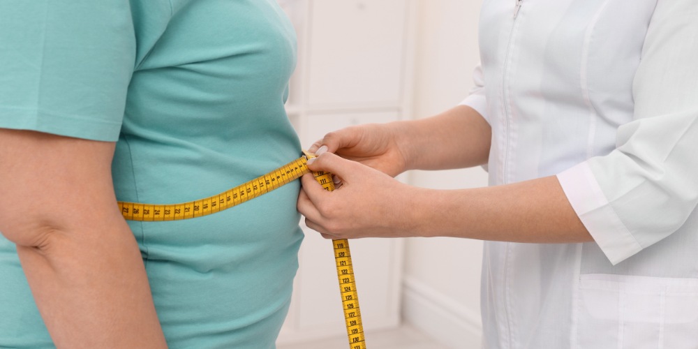 a medical professional in a white lab coat measuring a patient's waist