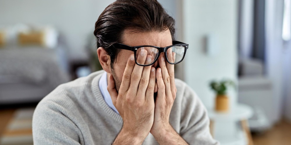 a man rubbing his eyes