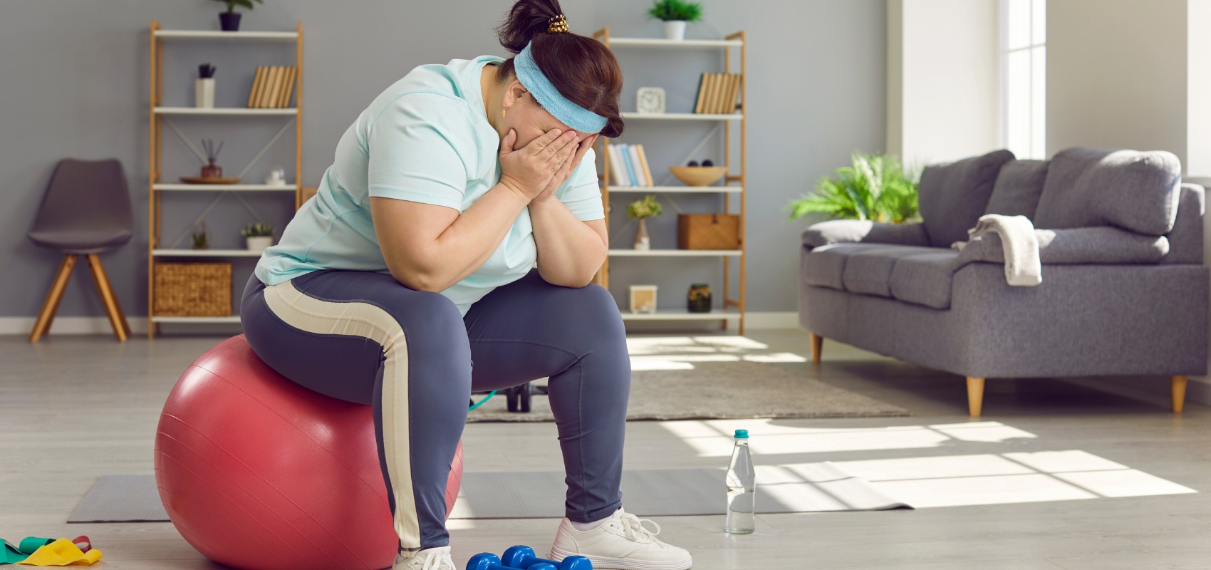 a woman sitting on a pink fitness ball in her living room