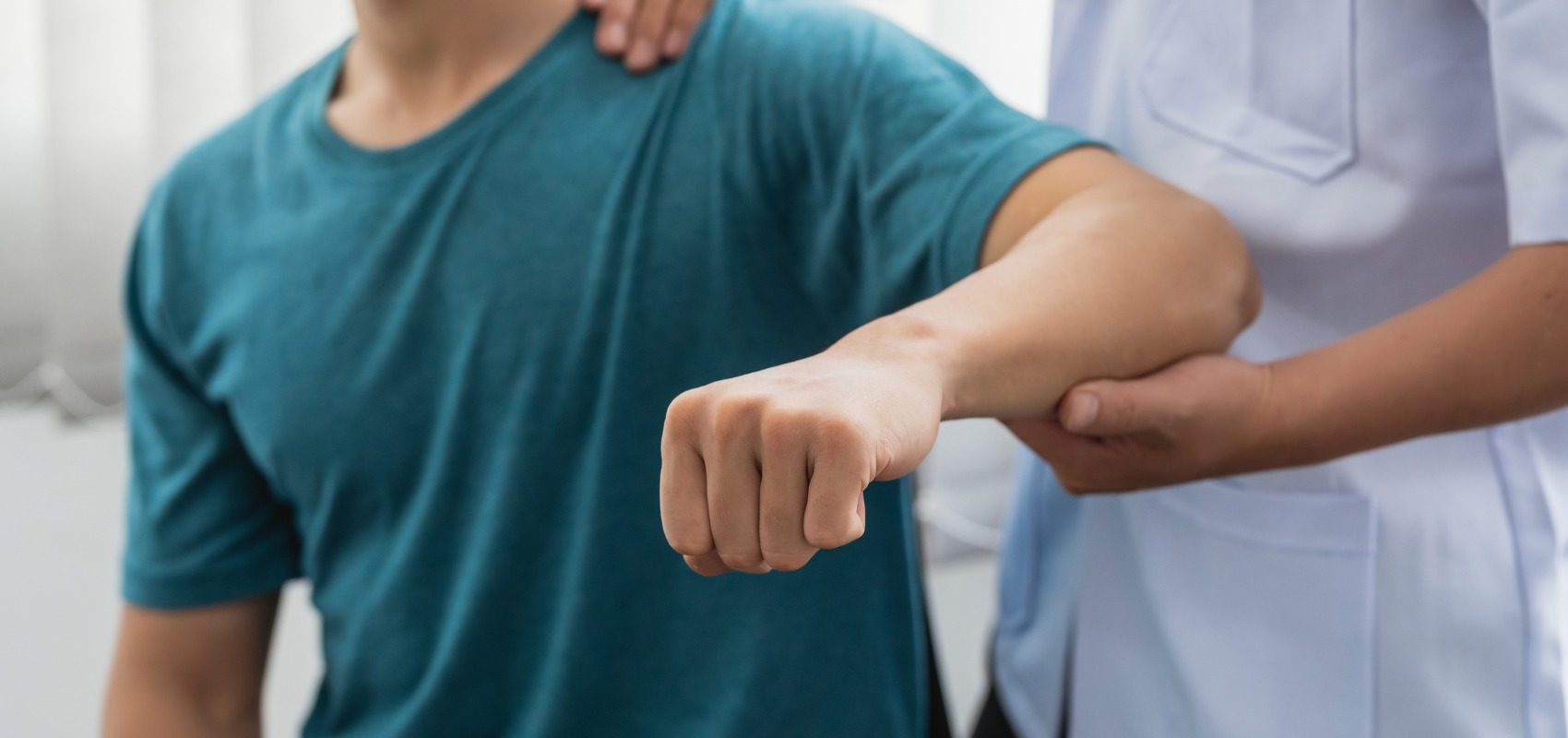 A therapist supports a patient's arm and shoulder