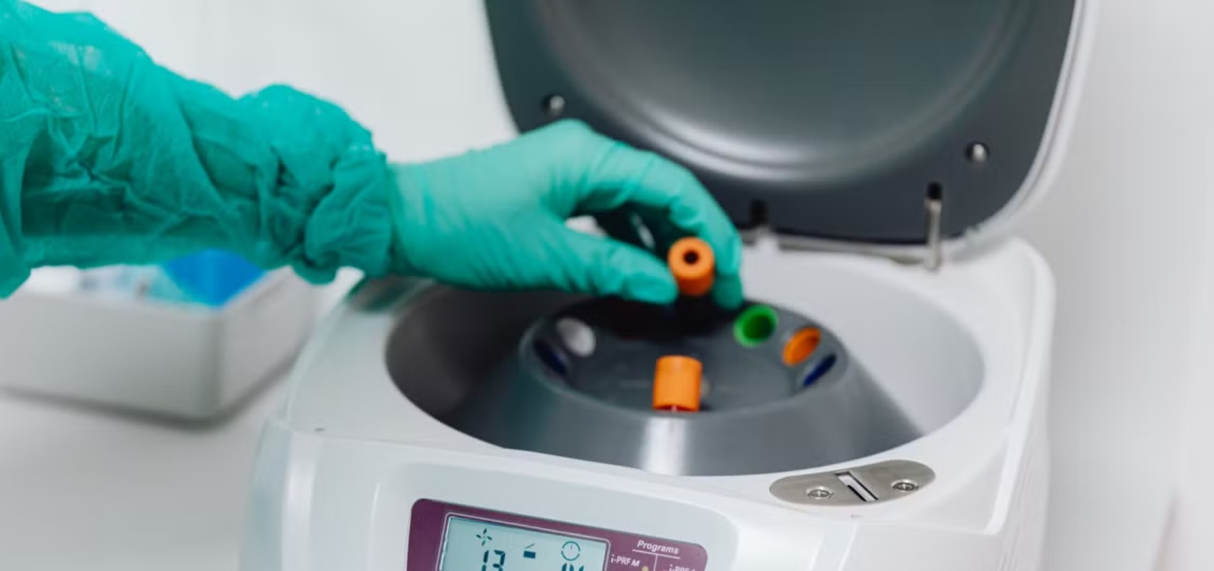 places blood tubes into a centrifuge machine to prepare a PRP treatment