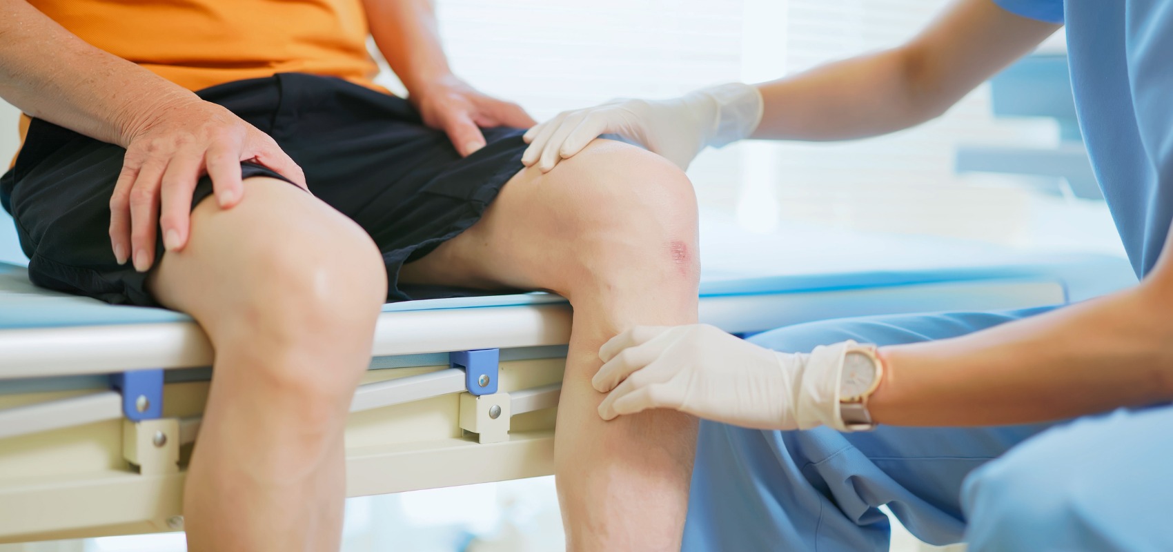 healthcare worker wearing gloves examines a patient's injured knee