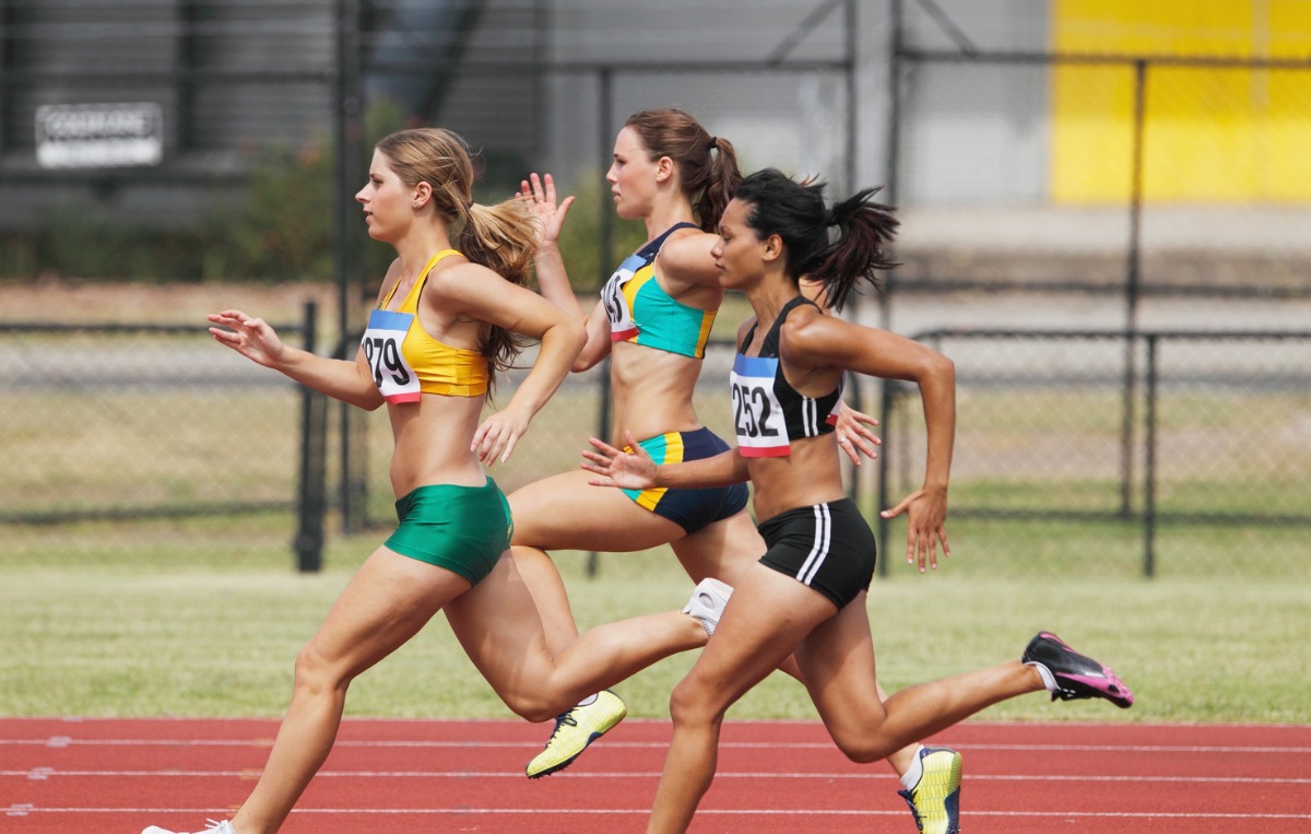 Three female athletes sprinting on a running track