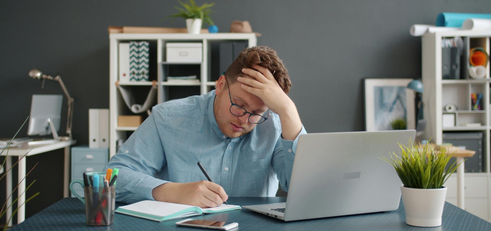 A stressed man holding his head while working