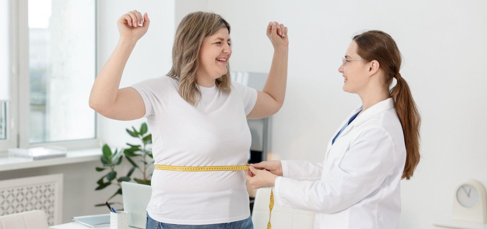 a female doctor measuring a celebrating woman's waist