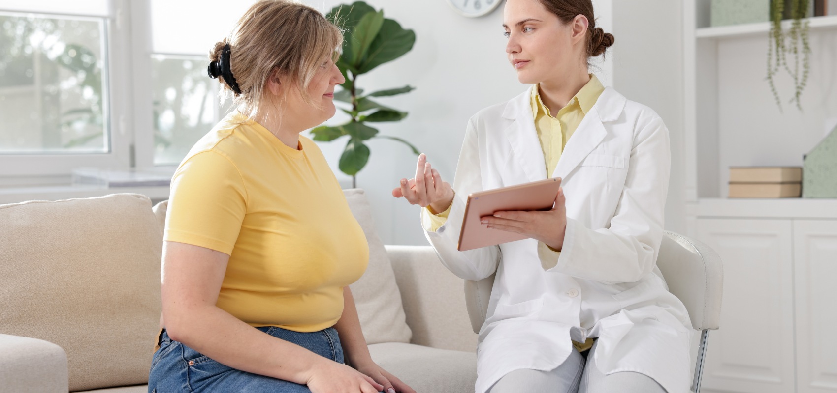 female doctor holding a tablet while consulting with a seated woman