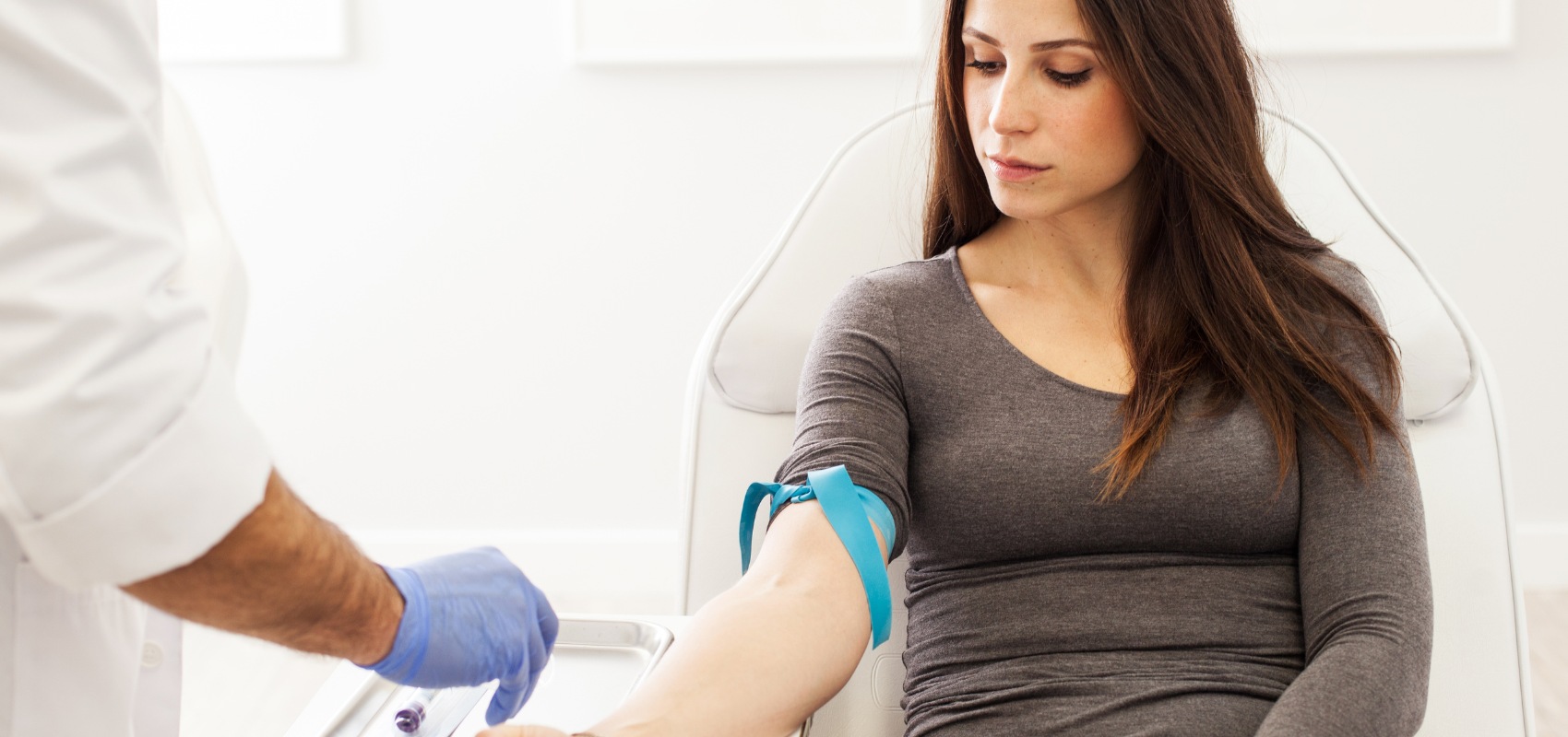 medical professional prepares to draw blood from a seated woman