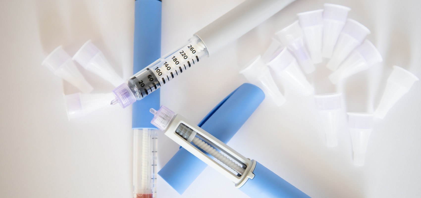 two medical injection pens, caps, and scattered pen needle caps