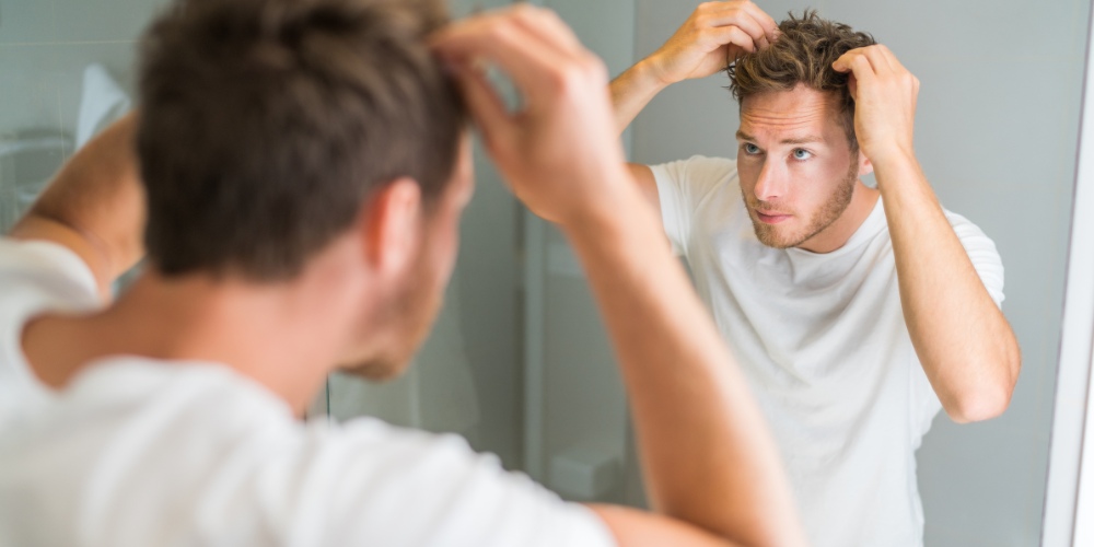 A young man looking at his reflection in a bathroom mirror
