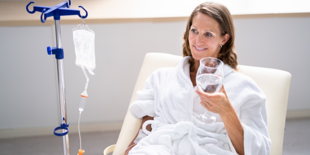 A smiling woman in a white bathrobe sitting in a chair