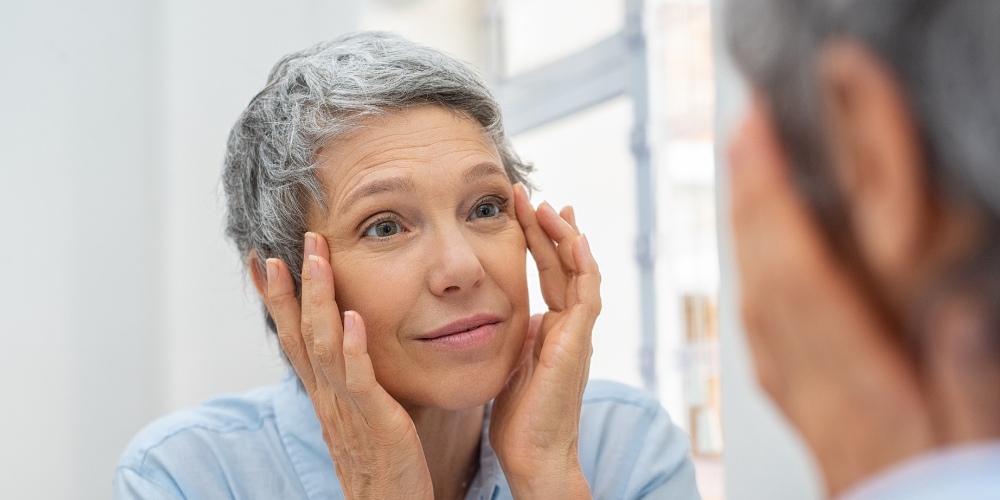 A woman with short grey hair looking into a mirror