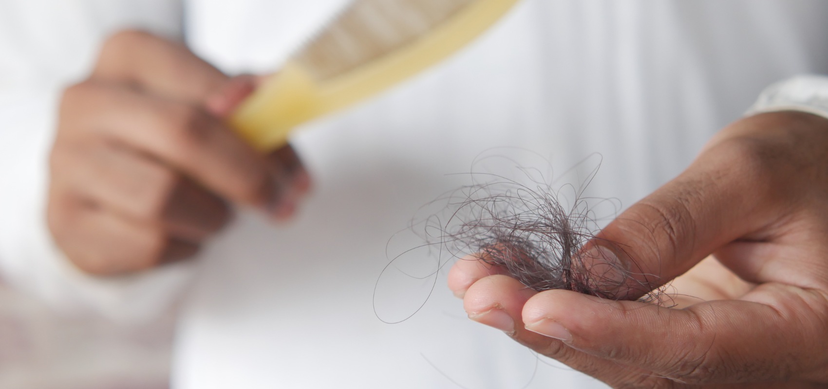 a person's hand holding a loose clump of dark hair