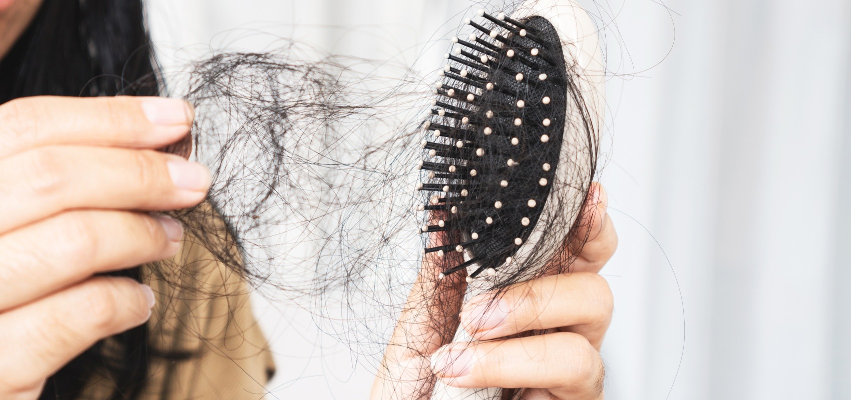 A close-up of hands pulling a large tangle of dark hair