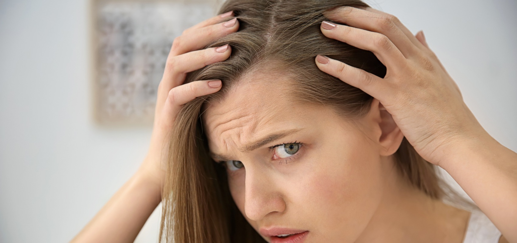 A concerned woman parts her hair with her hands
