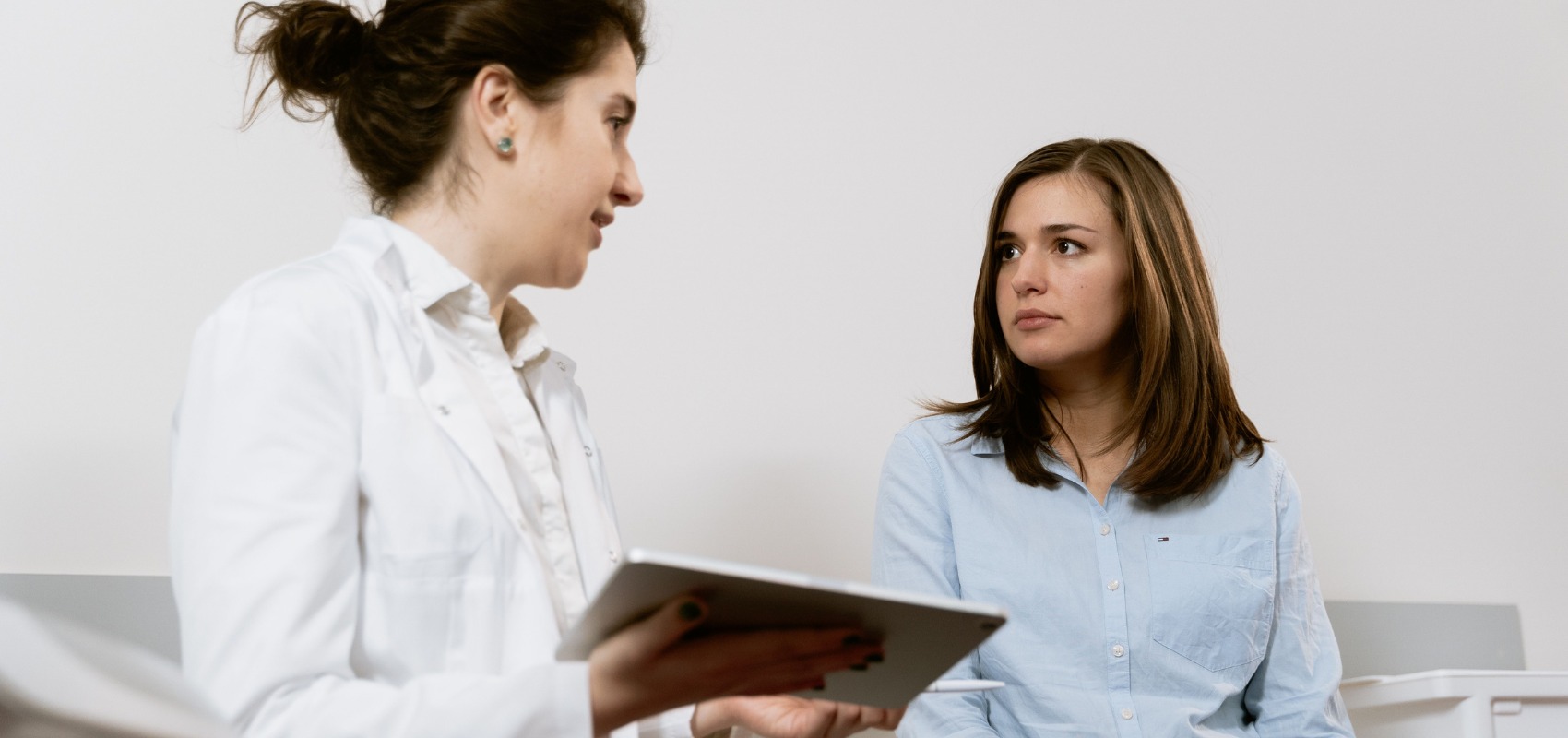 female doctor in a white coat speaking to a seated patient