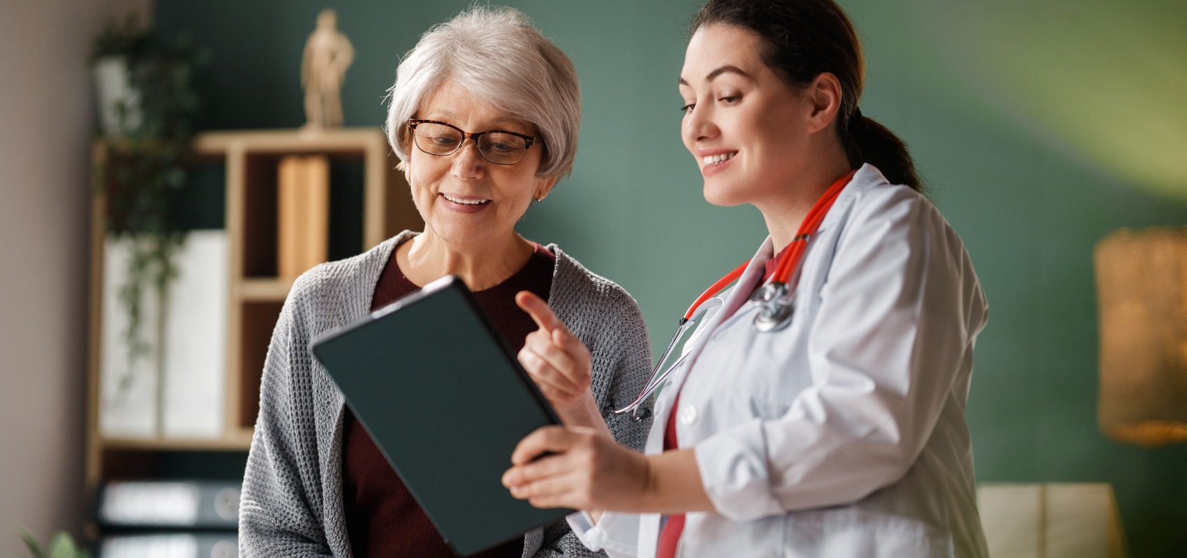 a doctor showing information on a digital tablet to an elderly woman