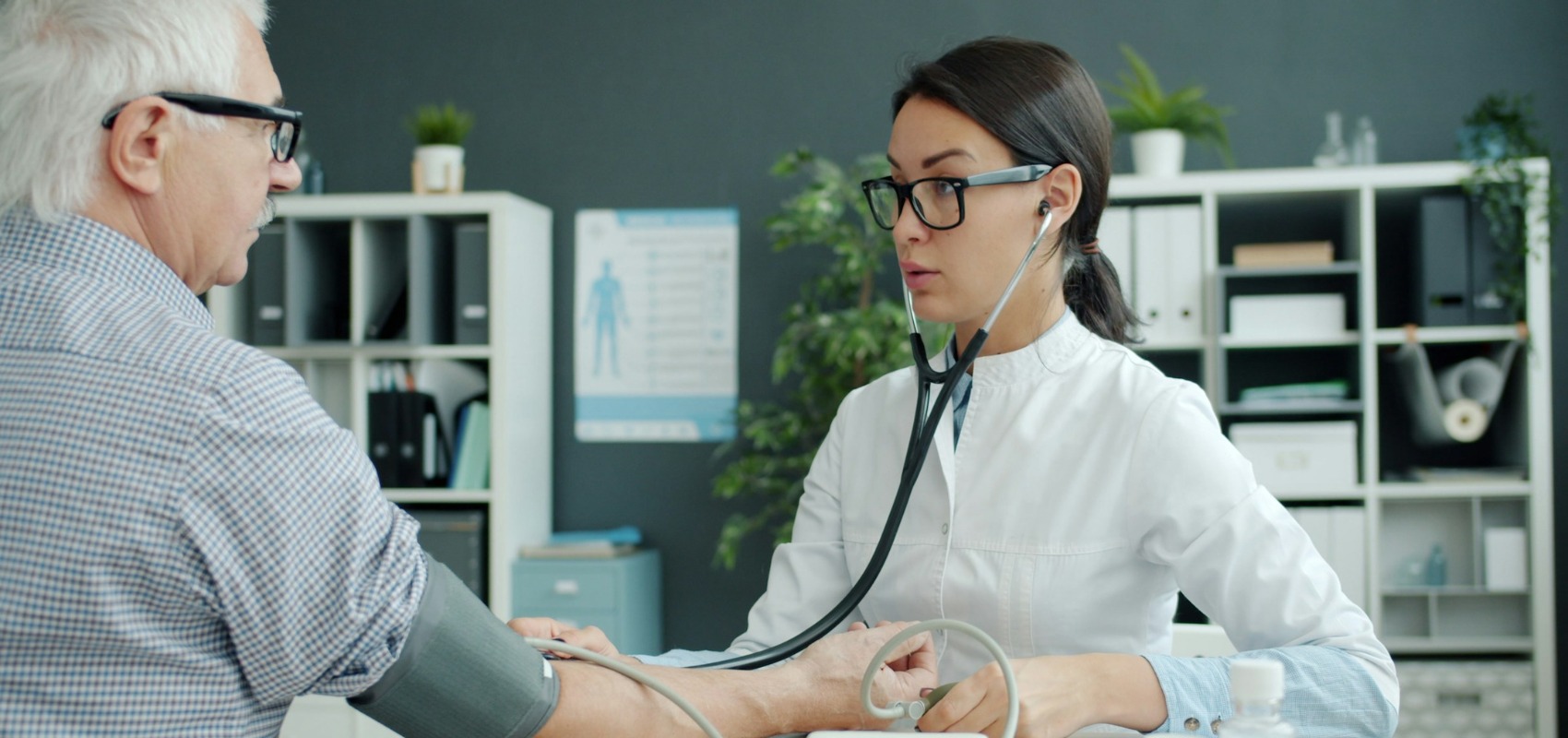 a doctor uses a stethoscope while checking a man's blood pressure