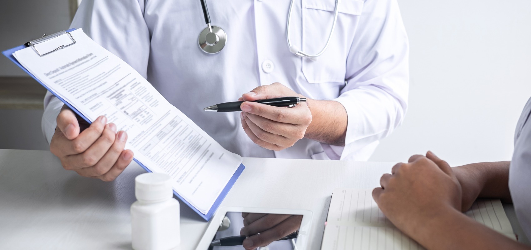doctor pointing a pen at a clipboard