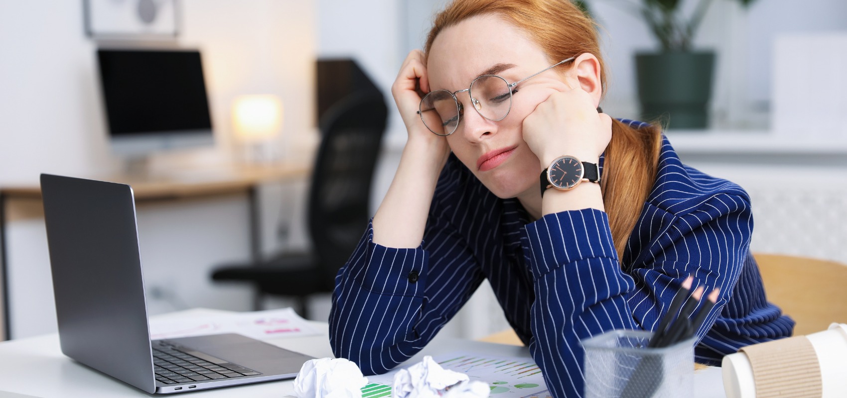 Tired businesswoman sitting at a desk with eyes closed