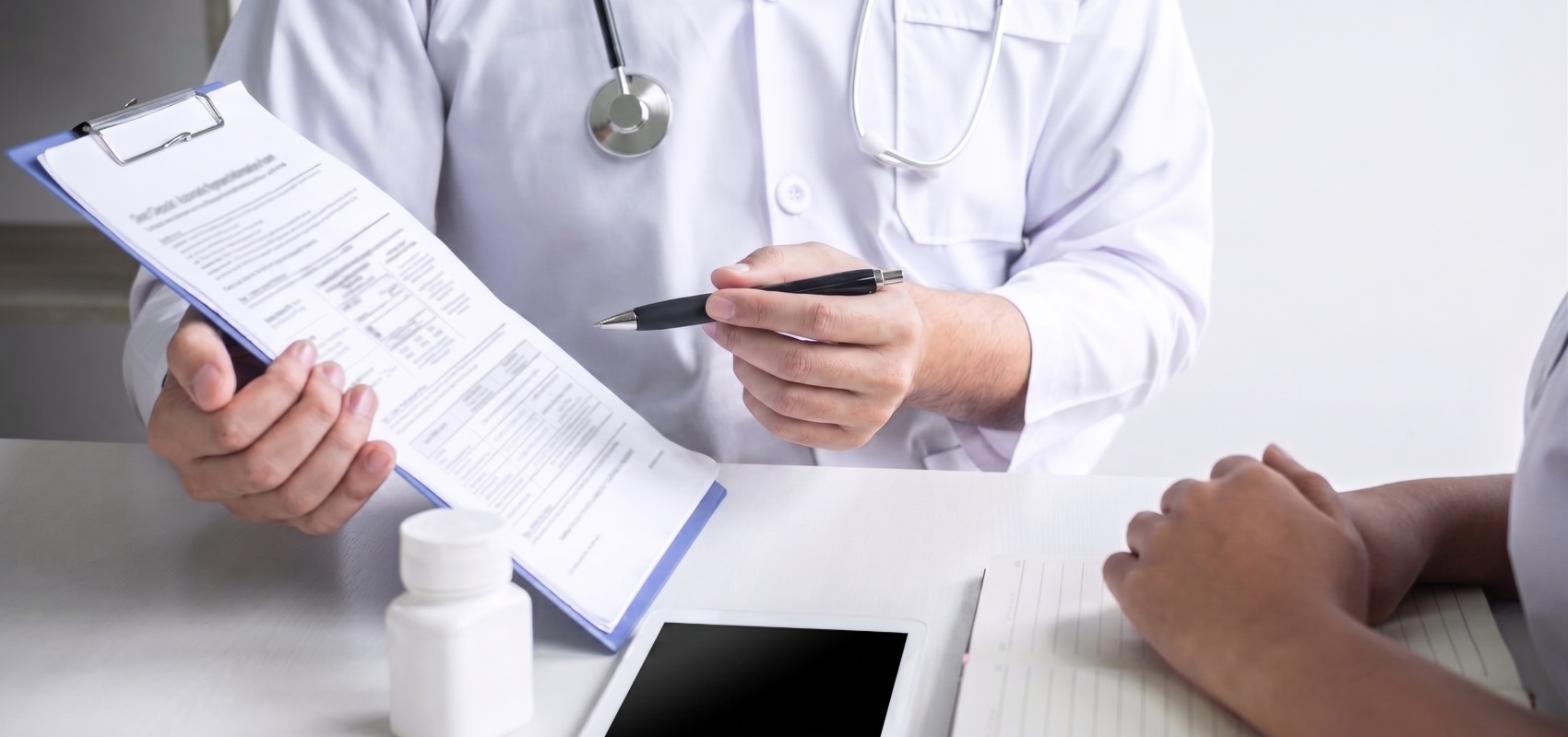 doctor pointing a pen at a clipboard