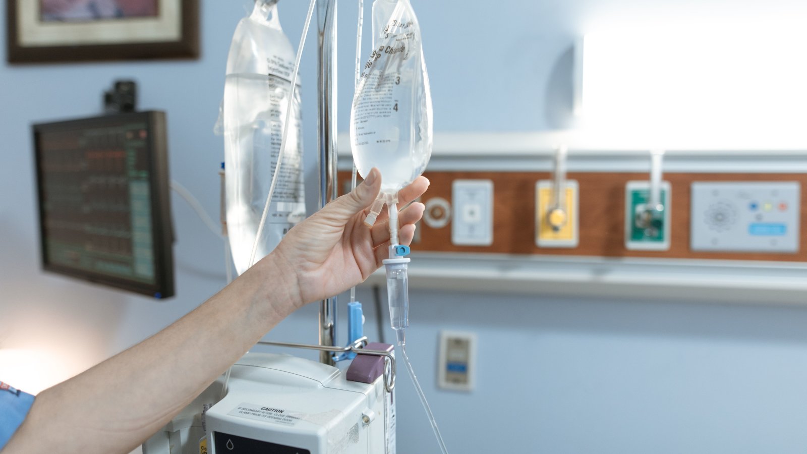 Close-up of an IV drip and patient hand in a hospital room illustrating IV therapy treatment.